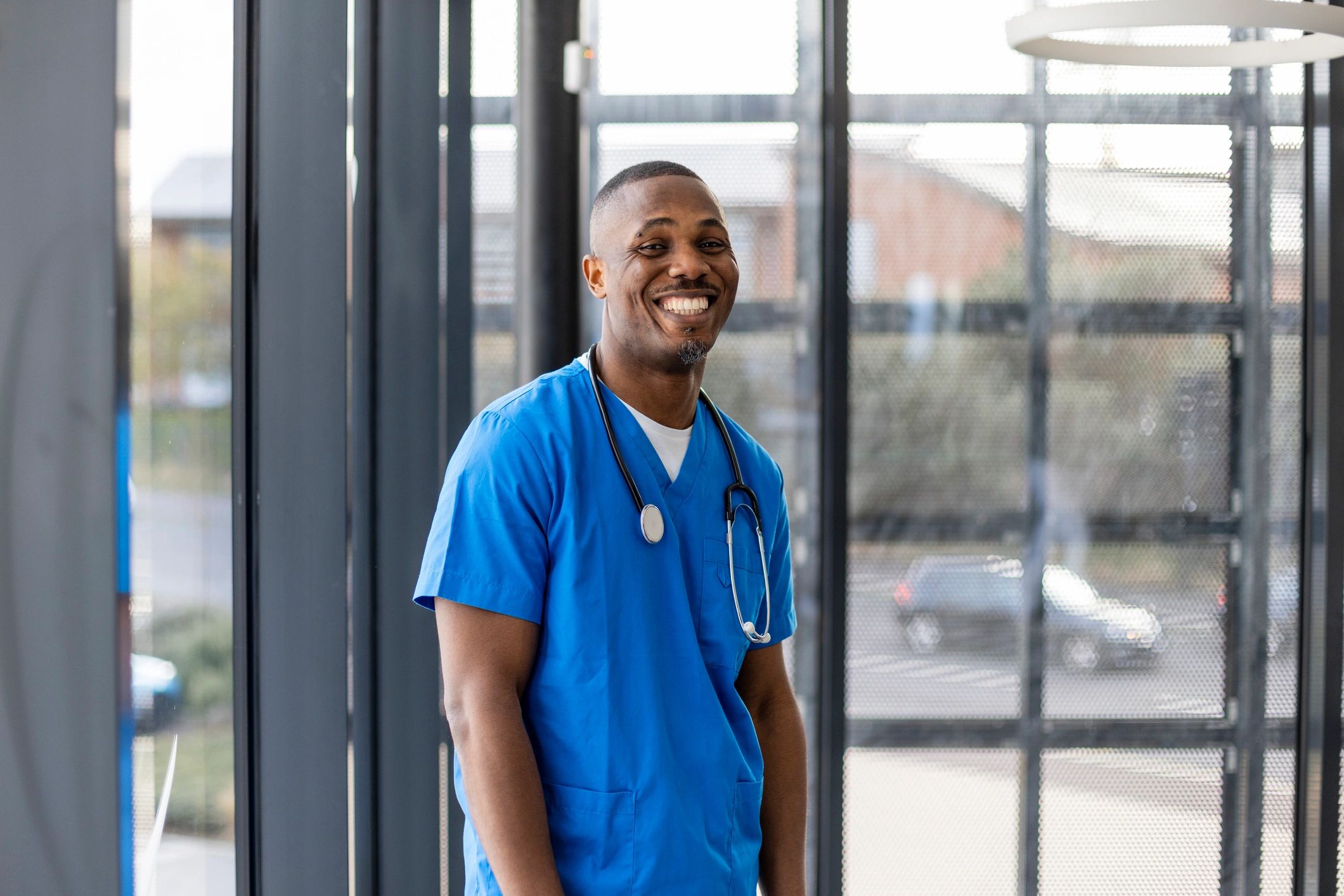 Physician in scrubs with stethoscope, looking at camera